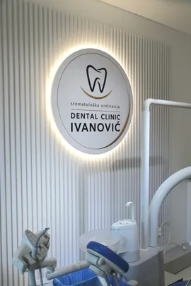 Osvetljen znak Dental Clinic Ivanović na zidu ordinacije, pored stomatološke stolice